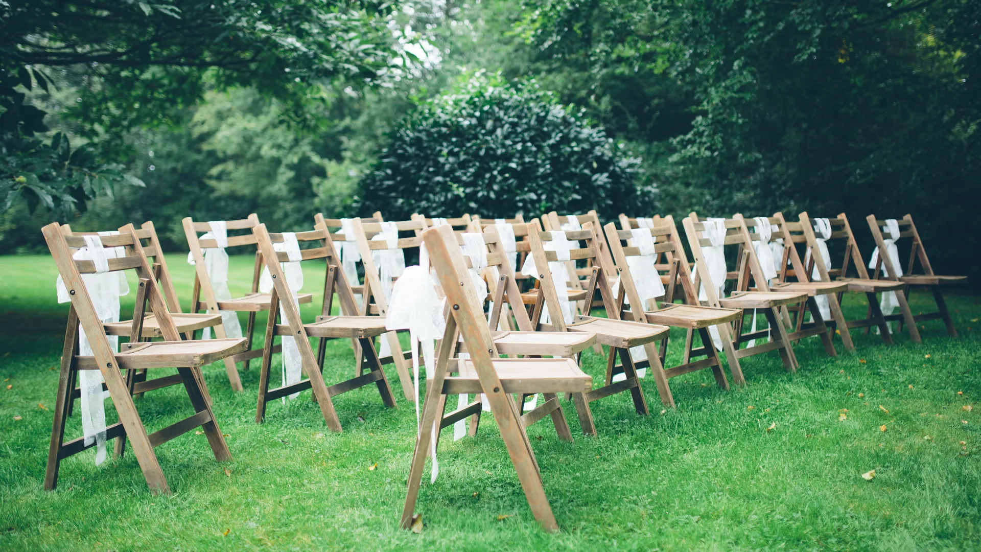 Houten stoelen op grasveld, buitenopstelling voor evenement.