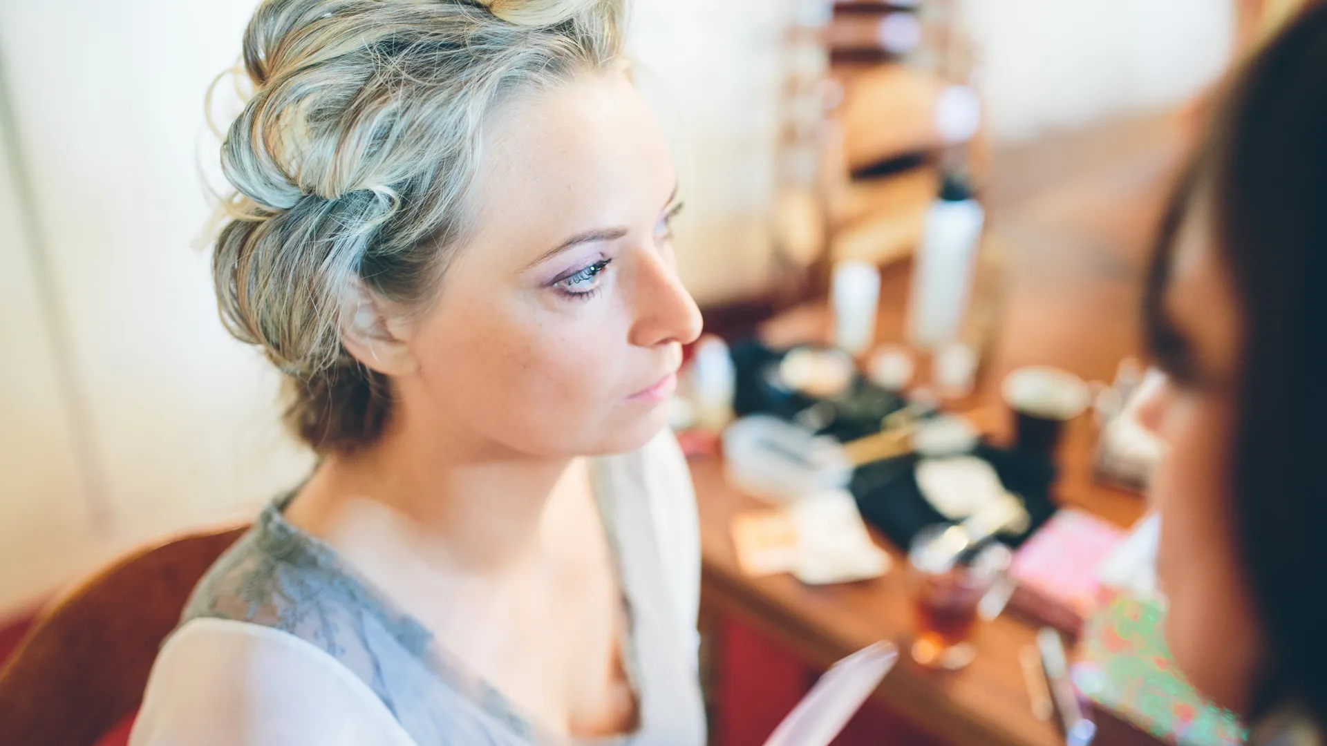 Vrouw bij kaptafel met make-up en haarproducten.