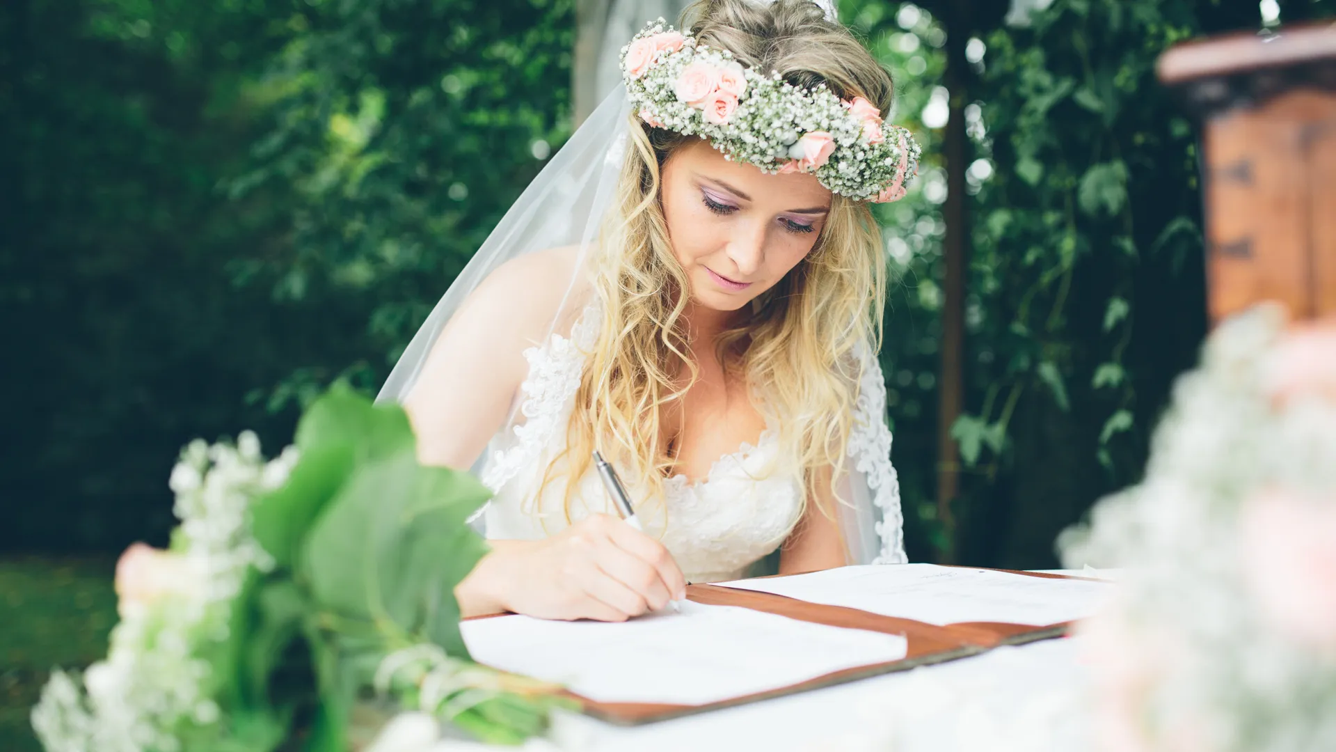 Bruid tekent huwelijksdocument buiten in de natuur.