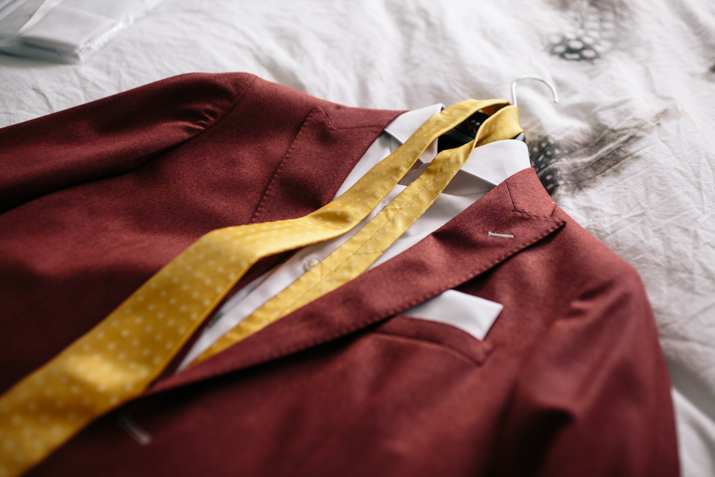 Bordeaux pak met gele stropdas op bed