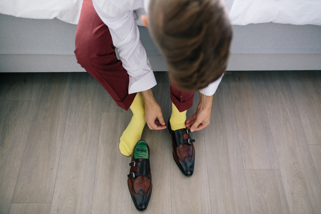 Man trekt gele sokken en bruine schoenen aan.