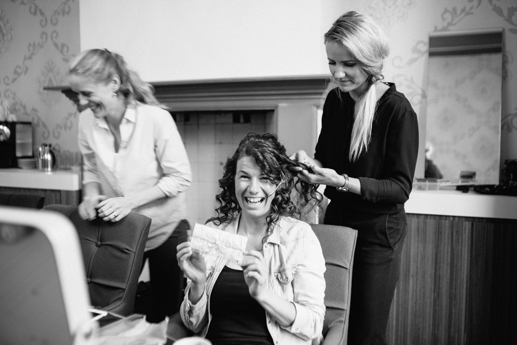 Vrouwen lachen tijdens haarstyling in salon