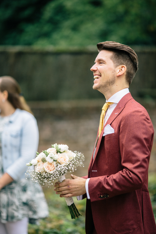 Man in rood pak met bloemenboeket.