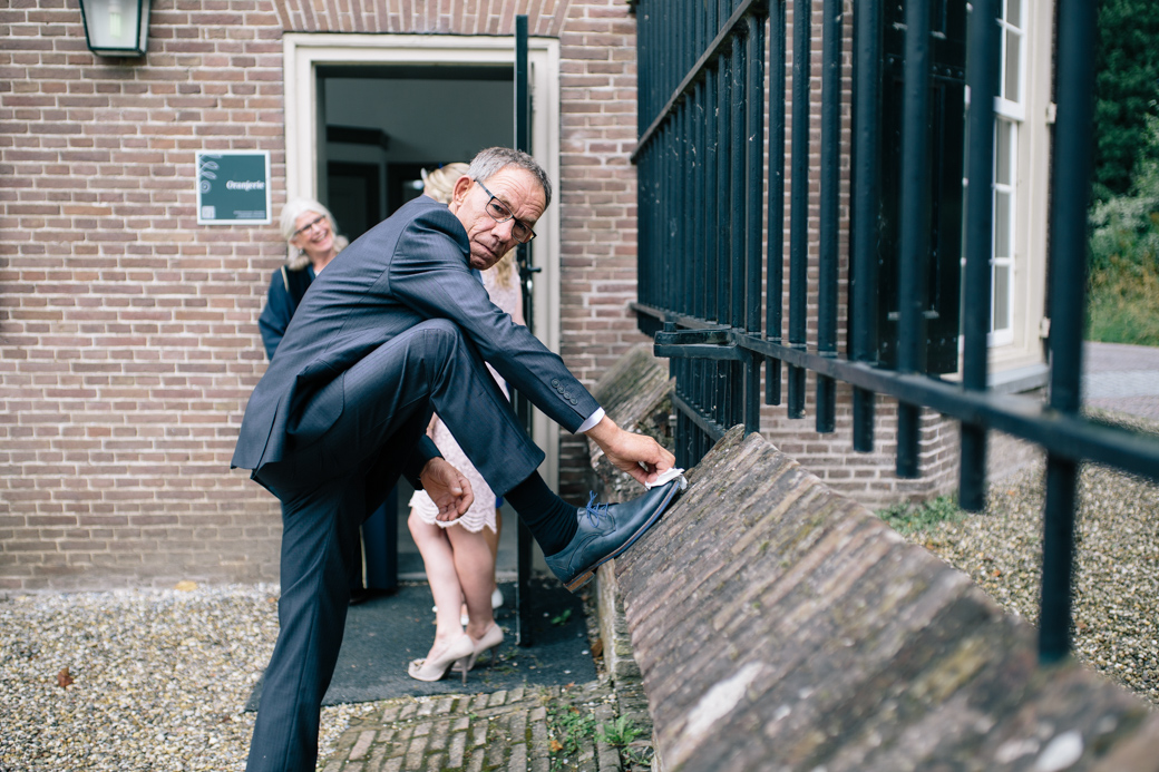 Man poetst schoen buiten gebouw.