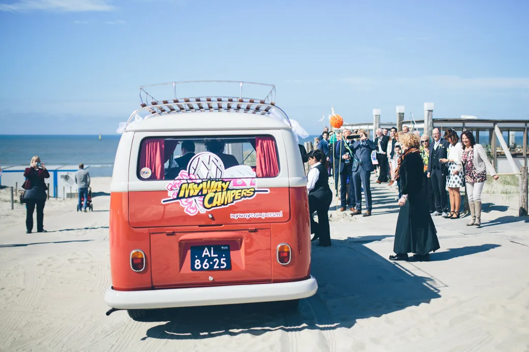 Bruiloft met retro-camper op het strand.