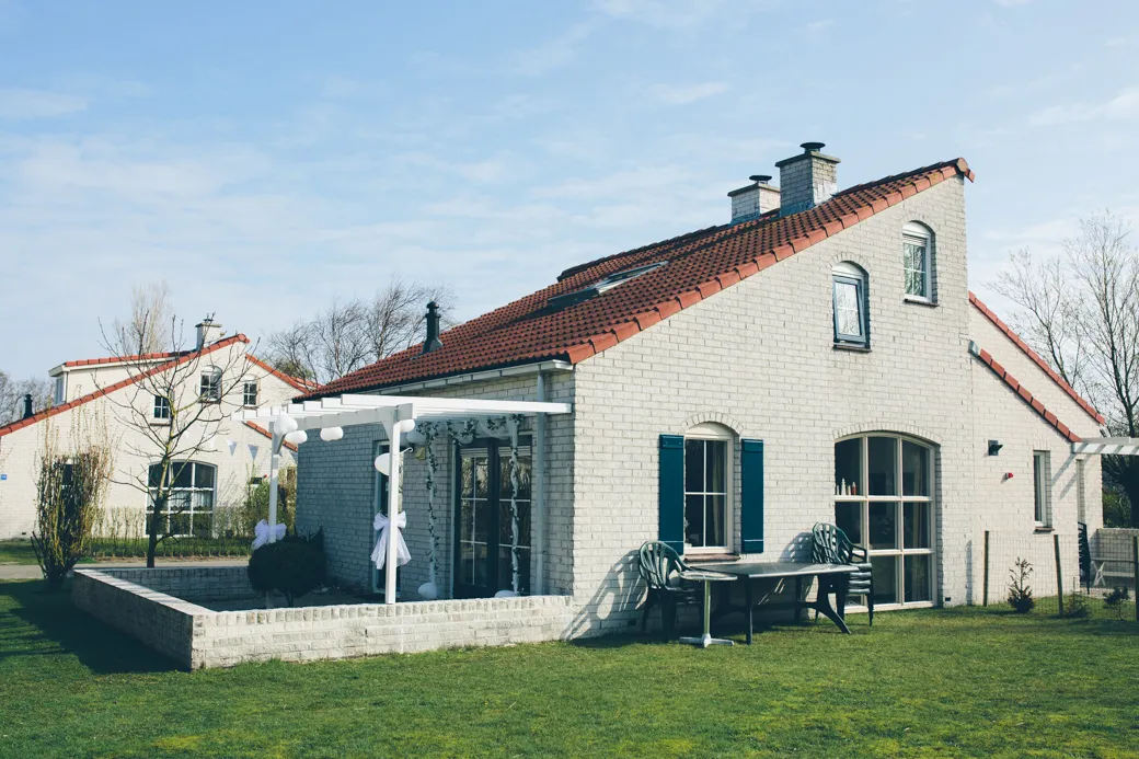 Bakstenen huis met rode dakpannen en tuin.