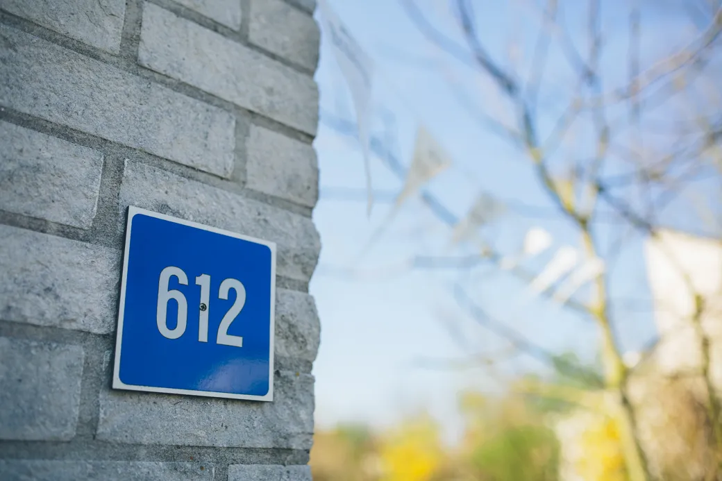 Blauw huisnummerbord 612 op stenen muur