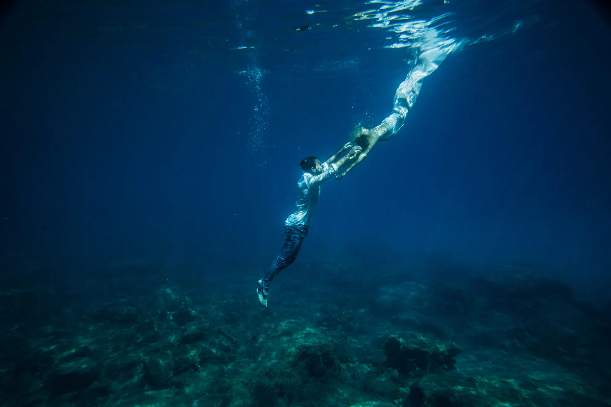 Onderwater dansende mensen in blauwe zee
