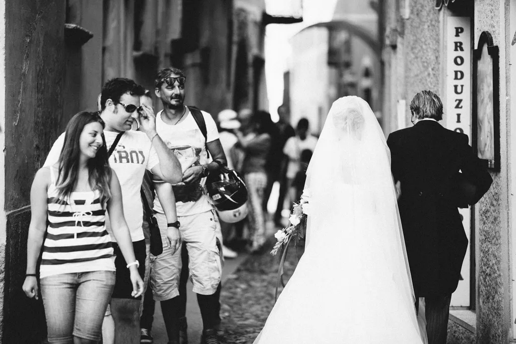 Bruiloftskoppel wandelt door straat, voorbijgangers kijken toe.